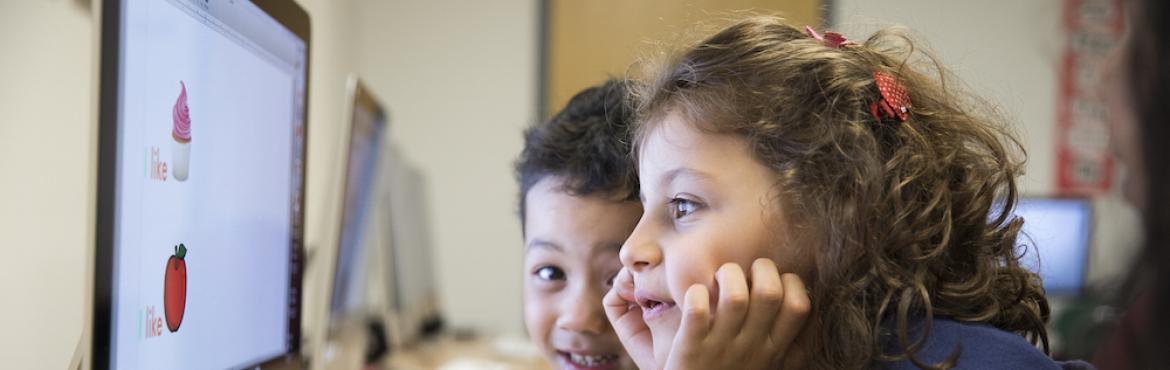 Two children looking at a computer.